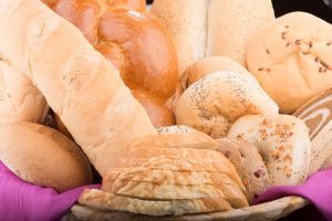 Tasty Pastry Tasty Treats: Overflowing Basket of a Variety of Bread (rolls, sliced, bagels, plaited)