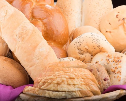 Tasty Pastry Tasty Treats: Overflowing Basket of a Variety of Bread (rolls, sliced, bagels, plaited)