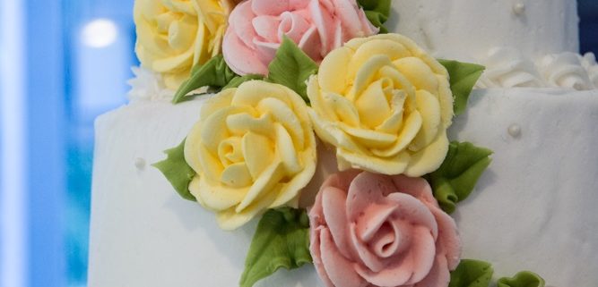 Tasty Pastry Custom Cakes: Three-tiered cake with white icing & cascading pink/yellow icing flowers