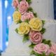 Tasty Pastry Custom Cakes: Three-tiered cake with white icing & cascading pink/yellow icing flowers