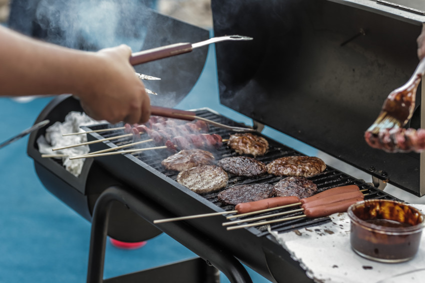 open grill with hamburger patties, hot dogs, and sausage cooking